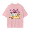 A light pink faded short-sleeve t-shirt featuring a graphic print of a cougar lying down in front of painted lady houses.