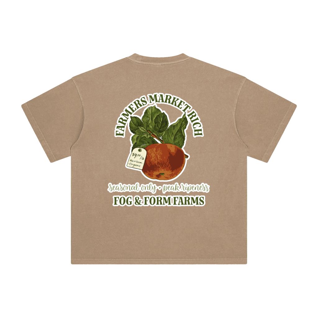 A faded tan short-sleeve t-shirt shown from the back, featuring a large graphic print of a red apple with leaves and text that reads 'FARMERS MARKET RICH', 'seasonal only - peak ripeness', and 'FOG & FORM FARMS'.