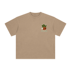 A light brown short-sleeve crewneck t-shirt with a small graphic on the left chest showing an apple.